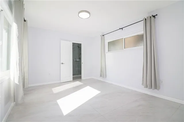 a view of an empty room with closet and a window