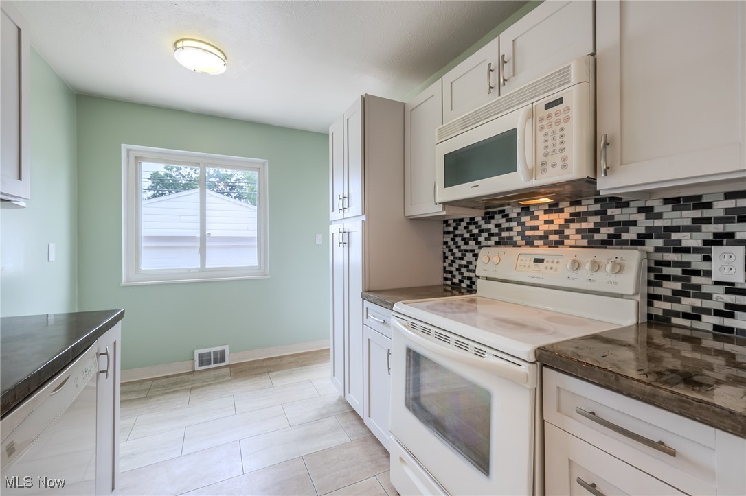29971 Regent Road Wickliffe, OH 44092 - Photo 9 of 39 Kitchen featuring white appliances, dark countertops, decorative backsplash, and light tile patterned floors