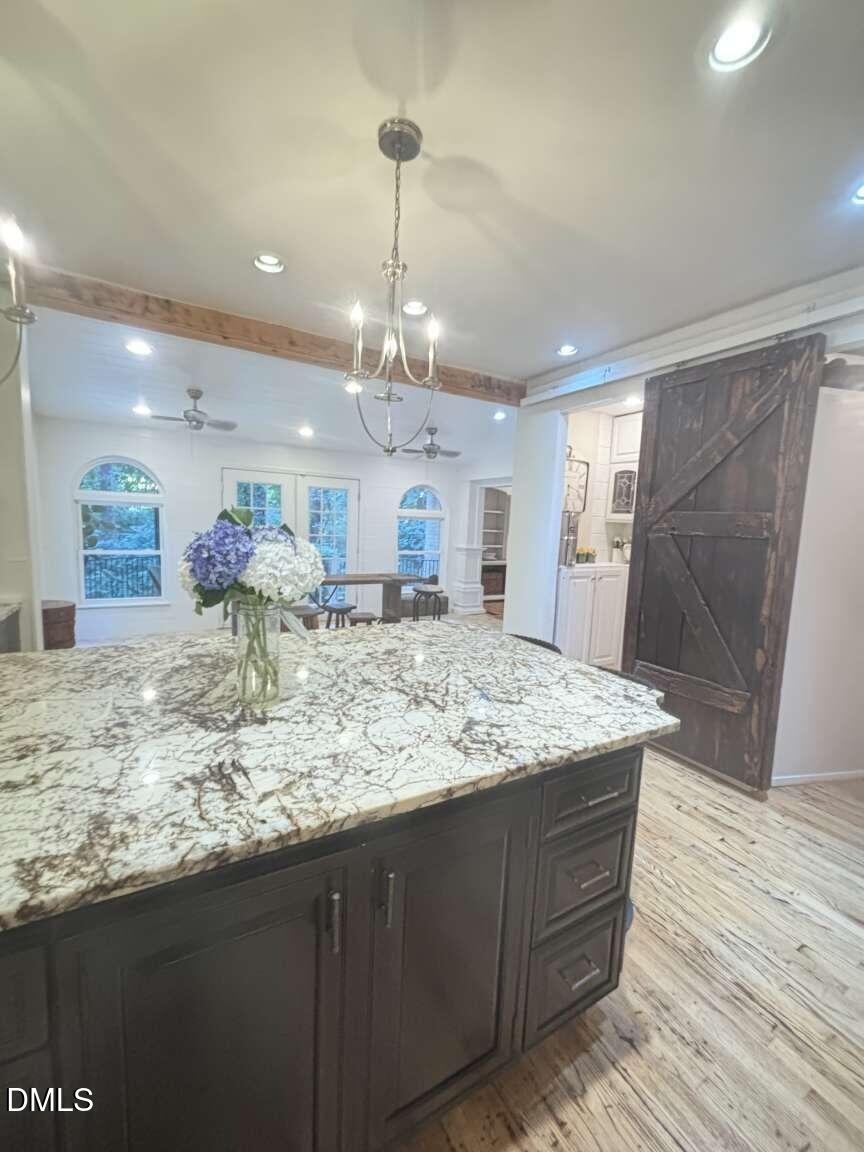 1204 Queensferry Road Cary, NC 27511 - Photo 35 of 50 a room with kitchen island granite countertop wooden floor and a chandelier