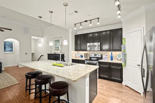 a kitchen with kitchen island a stove a refrigerator a sink a dining table and chairs