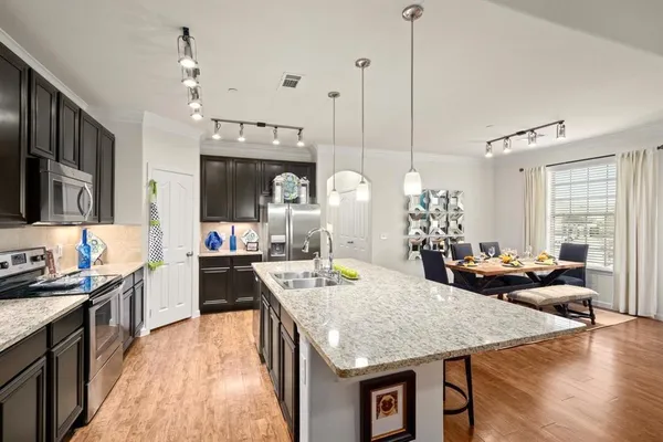 a kitchen with granite countertop a stove a kitchen island a dining table and chairs