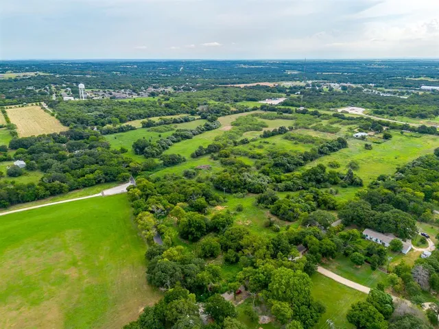 an aerial view of residential houses with outdoor space and trees