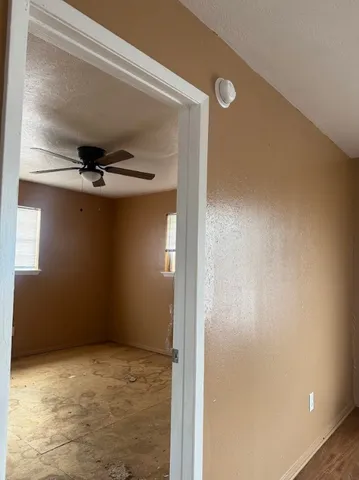 an empty room with a ceiling fan and window