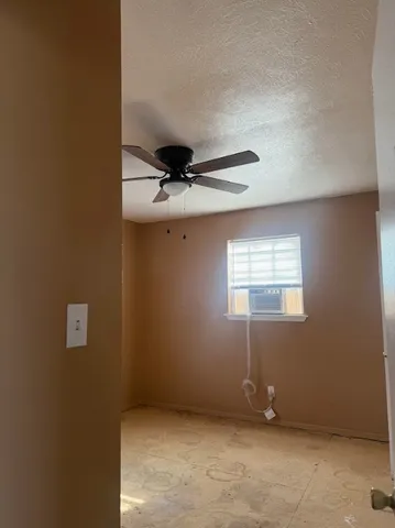 an empty room with wooden floor and a ceiling fan