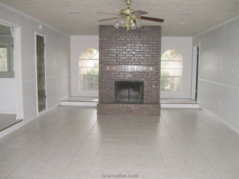 an empty room with windows cabinet and fireplace