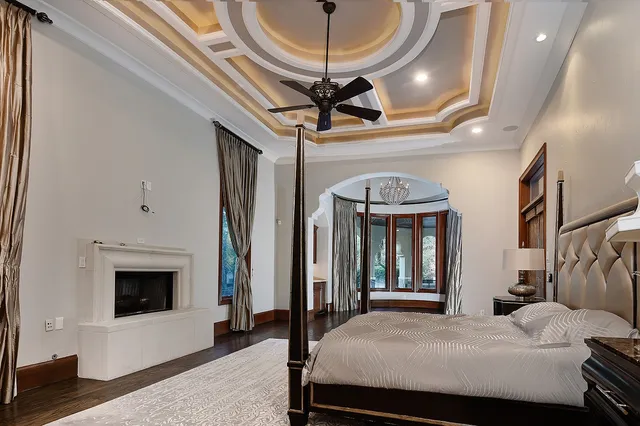 a bedroom with a bed a ceiling fan and a fireplace