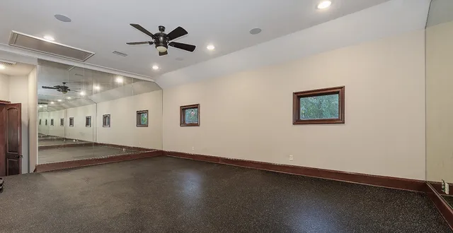 an empty room with ceiling fan and windows