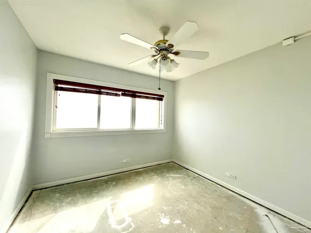 an empty room with a window and a chandelier fan