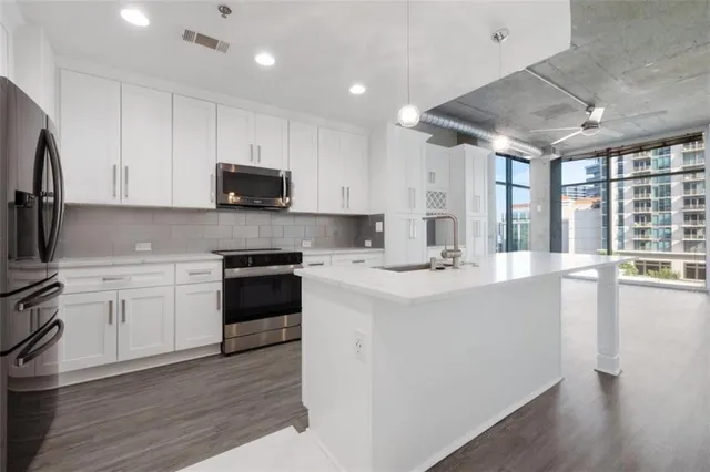 a kitchen with stainless steel appliances white cabinets a sink and a stove