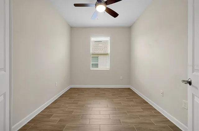 an empty room with a window and ceiling fan