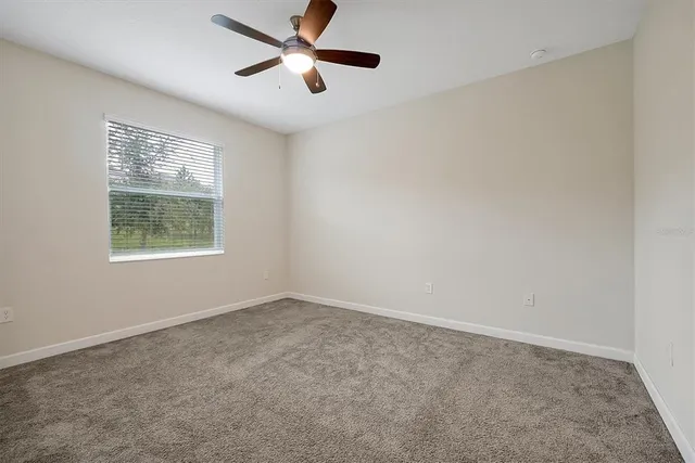 an empty room with a window and a ceiling fan