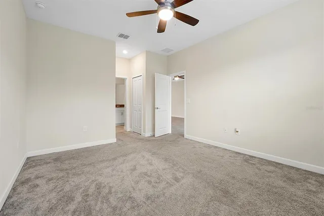 an empty room with chandelier fan and windows