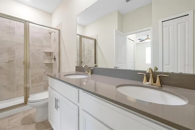 a bathroom with double vanity sink a mirror and a toilet