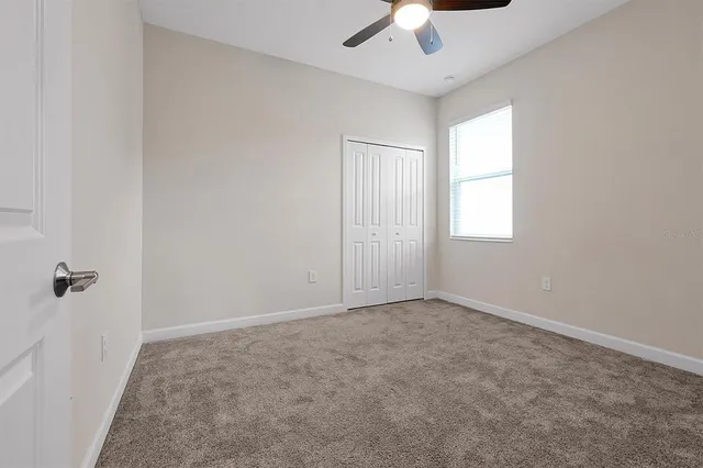 an empty room with windows and chandelier fan