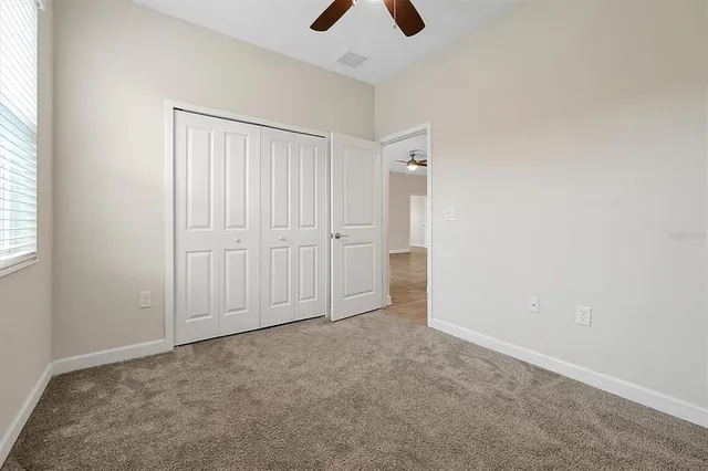 an empty room with chandelier fan and windows