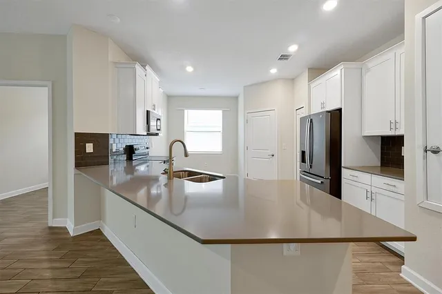 a large kitchen with stainless steel appliances a refrigerator a sink a stove a microwave and island