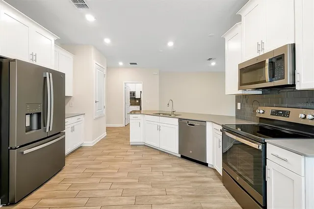 a large kitchen with a stove top oven a refrigerator and a sink