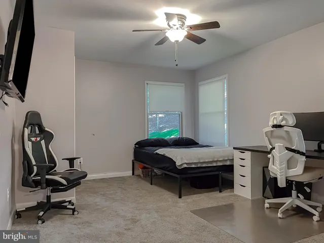 a bedroom with a bed a tv and wooden floor