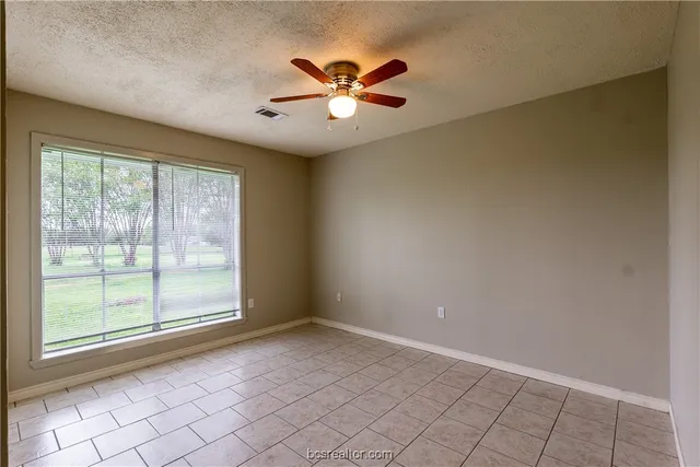 an empty room with windows and ceiling fan
