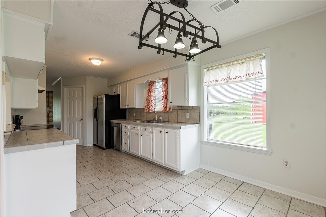 9812 Runaway Road College Station, TX 77845 - Photo 4 of 18 a kitchen with stainless steel appliances granite countertop a sink a stove a refrigerator cabinets and a window