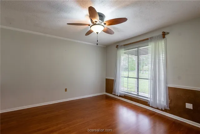 an empty room with wooden floor fan and windows