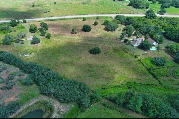 an aerial view of residential houses with outdoor space and trees
