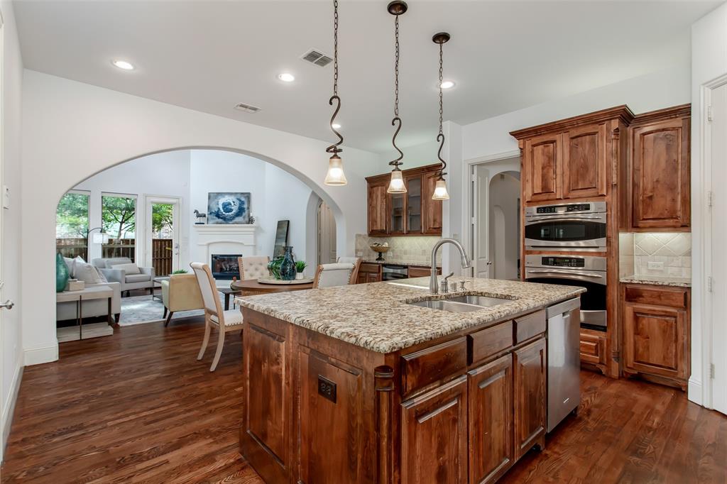 846 Deerfield Road Allen, TX 75013 - Photo 14 of 40 Gourmet kitchen featuring a central island with a double basin sink and granite countertop, rich wood-finish cabinetry, stainless steel double ovens, and recessed lighting