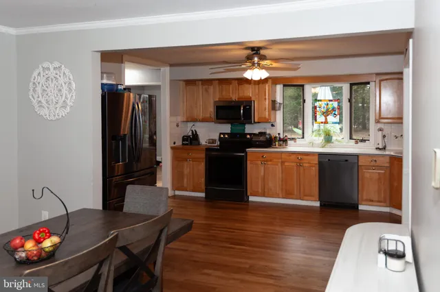 a kitchen with stainless steel appliances granite countertop a refrigerator a sink dishwasher a stove and a dining table with wooden floor