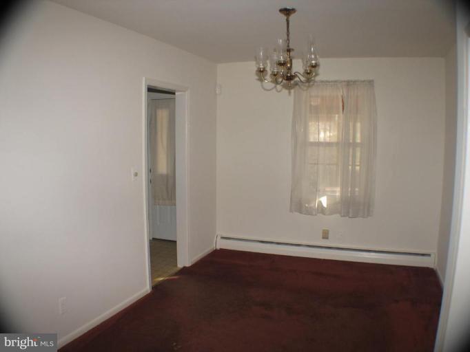 4131 Raleigh Road Pikesville, MD 21208 - Photo 4 of 11 an empty room with wooden floor and chandelier