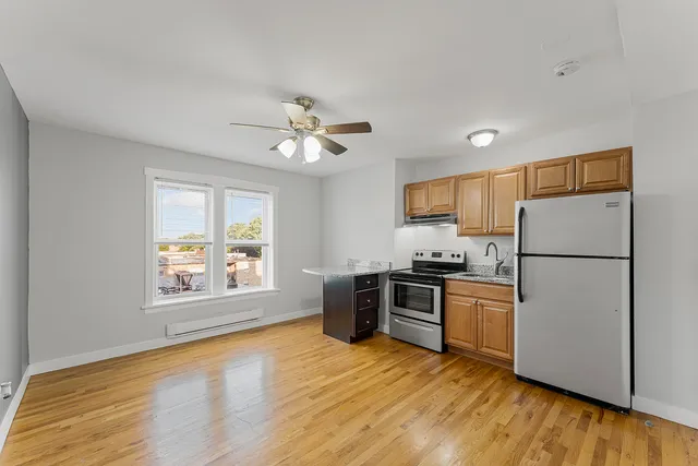 a kitchen with stainless steel appliances granite countertop a refrigerator a stove a sink dishwasher and a microwave oven with wooden floor