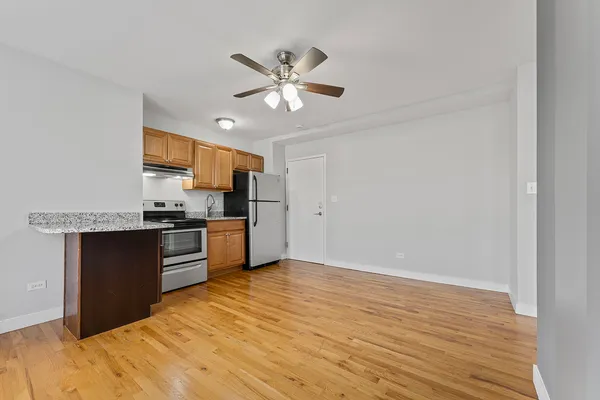 a kitchen with granite countertop a refrigerator and a stove top oven