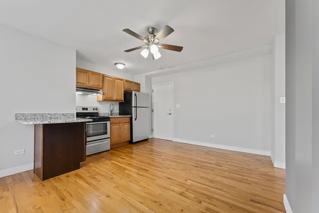a kitchen with granite countertop a refrigerator and a stove top oven