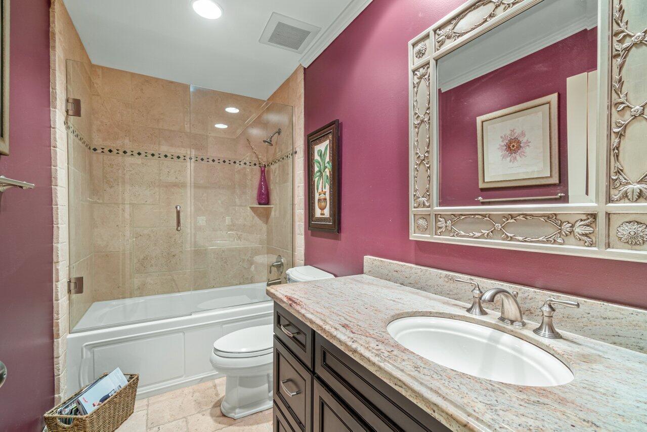 5861 Roebuck Road Jupiter, FL 33458 - Photo 12 of 74 a bathroom with a granite countertop toilet a sink a mirror a bathtub and shower
