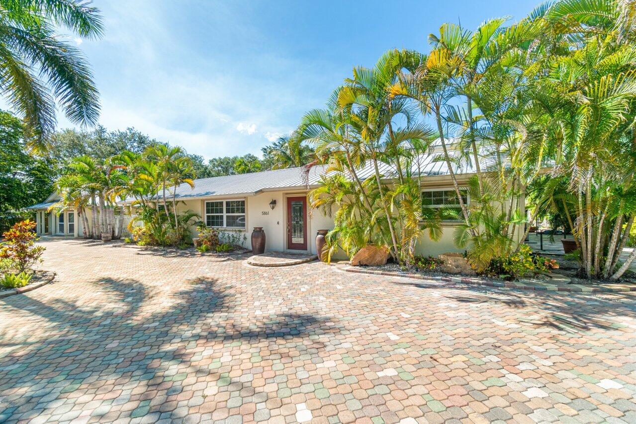 5861 Roebuck Road Jupiter, FL 33458 - Photo 2 of 74 a front view of a house with a yard and a garage