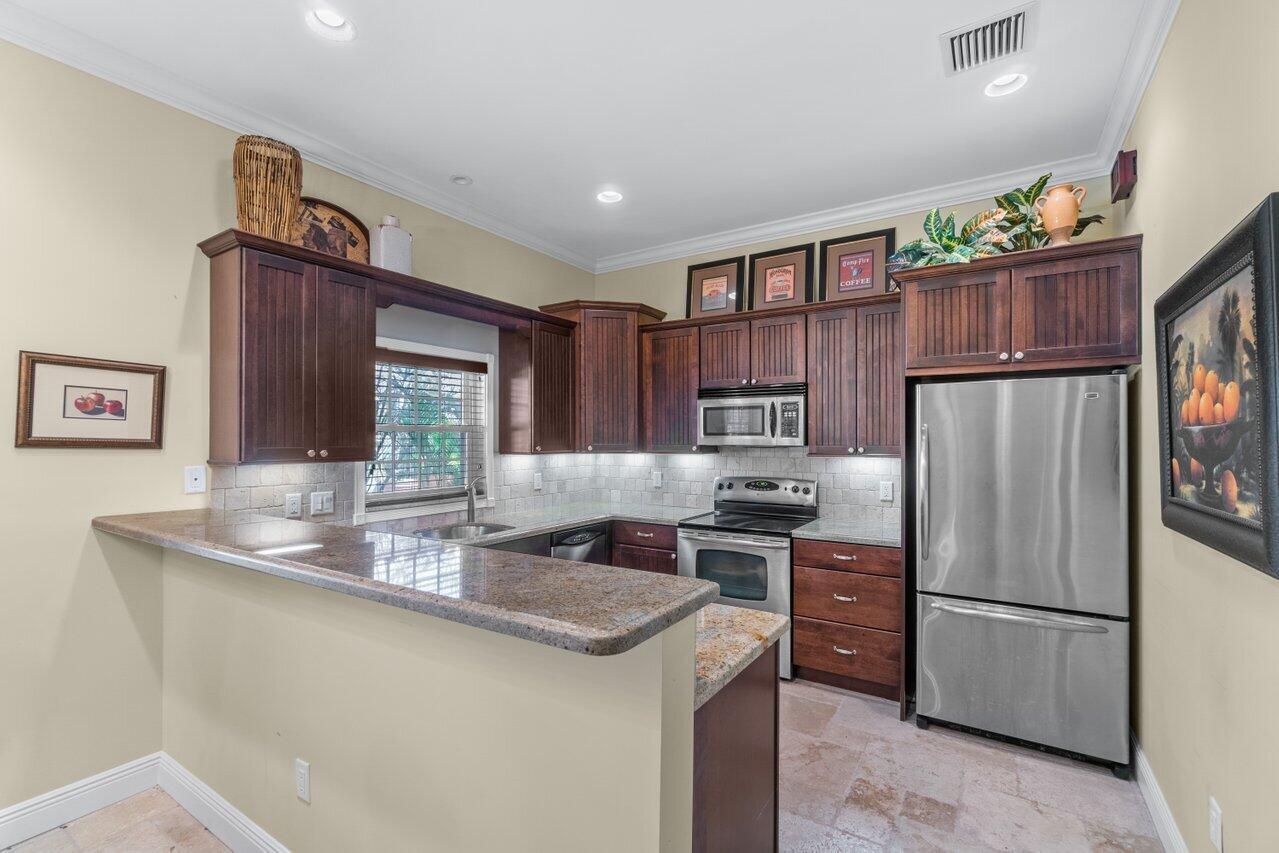 5861 Roebuck Road Jupiter, FL 33458 - Photo 33 of 74 a kitchen with kitchen island a counter top space a sink cabinets and stainless steel appliances