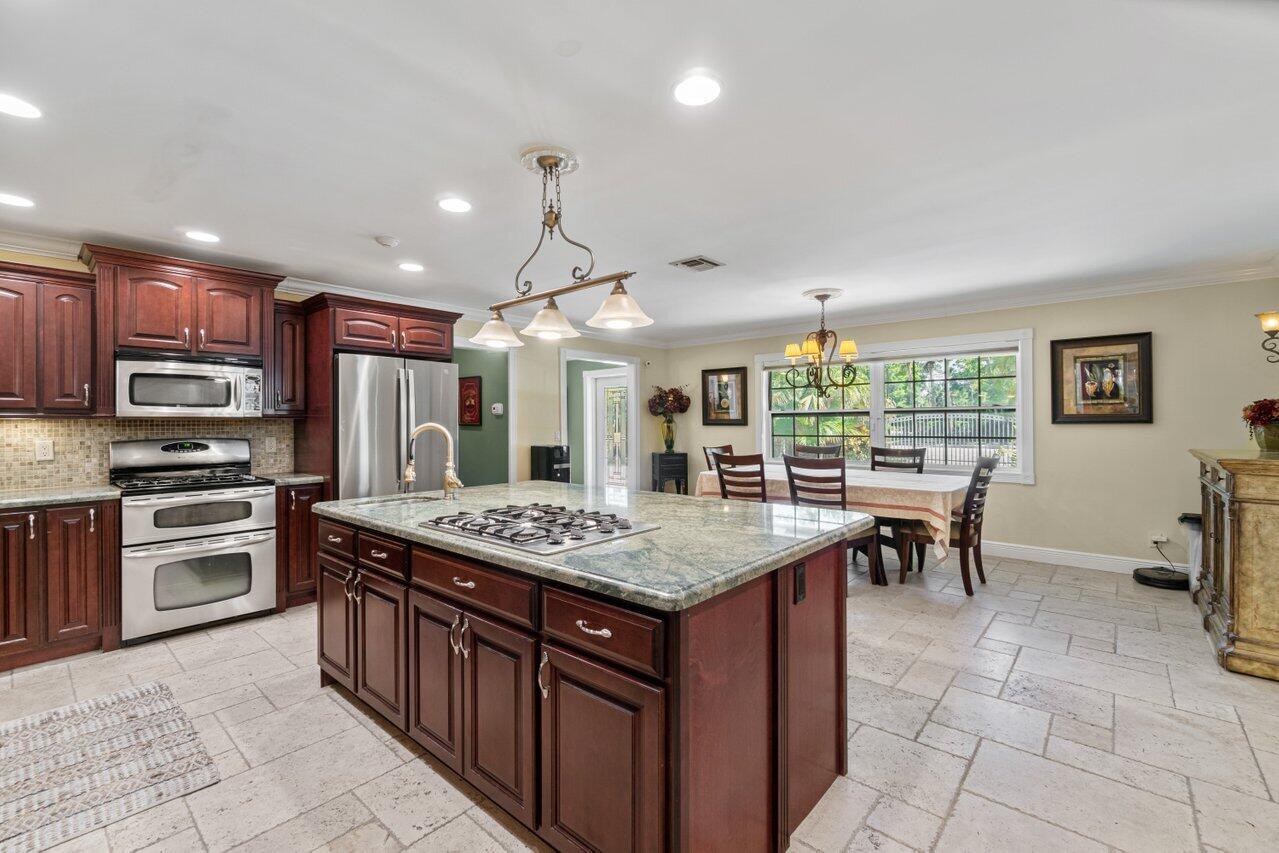 5861 Roebuck Road Jupiter, FL 33458 - Photo 6 of 74 a kitchen with stainless steel appliances granite countertop a stove top oven a sink dishwasher a dining table and chairs