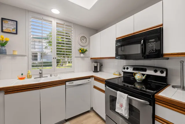 a kitchen with stainless steel appliances a sink a stove a microwave cabinets and a window