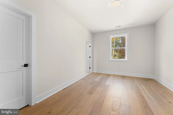 a view of an empty room with wooden floor and stairs
