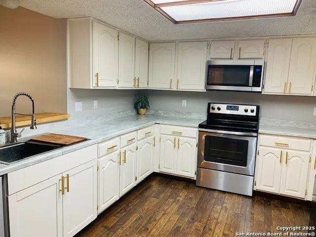 a kitchen with granite countertop white cabinets and appliances