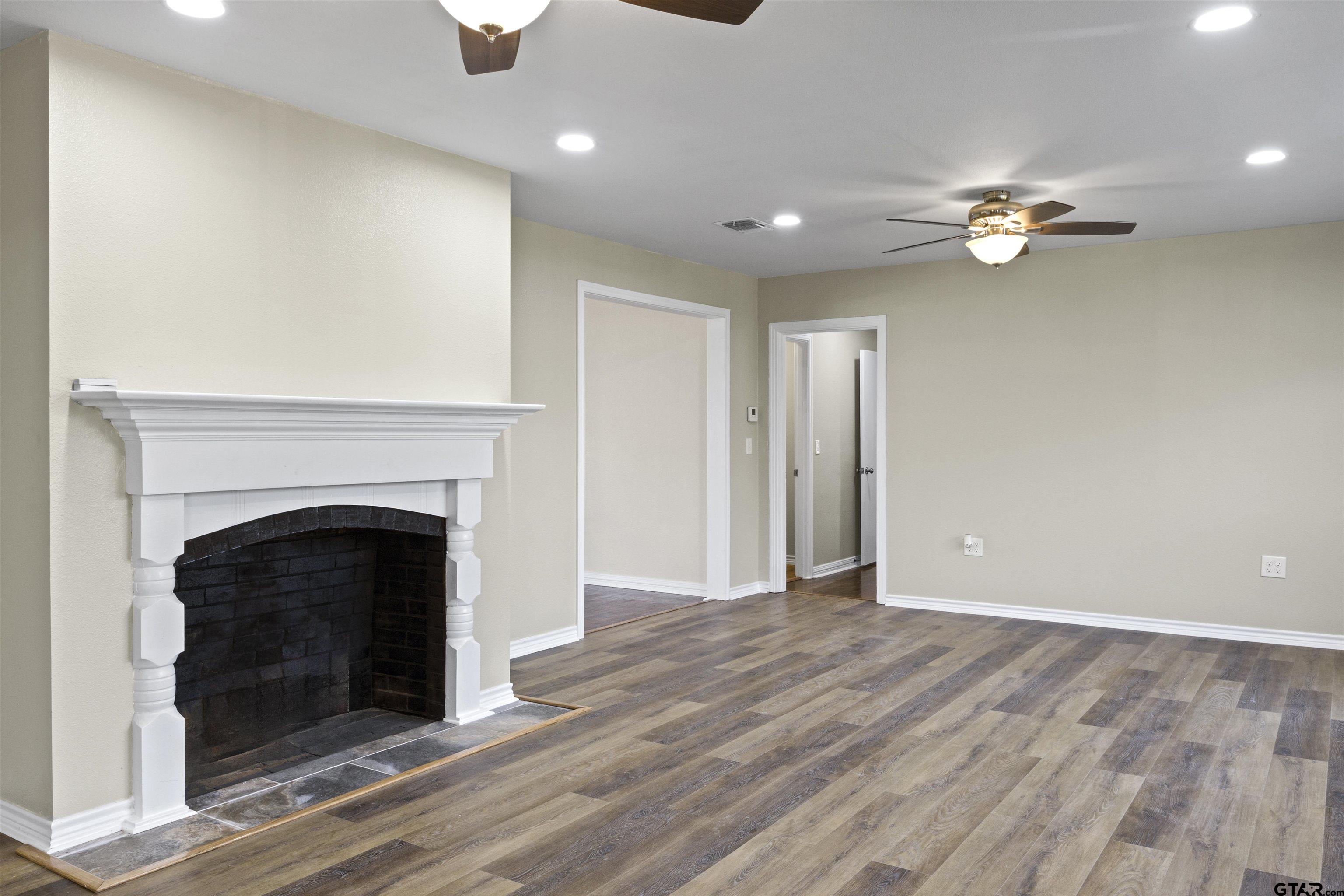 306 Quitman Street Pittsburg, TX 75686 - Photo 25 of 31 a view of a livingroom with a fireplace a ceiling fan and wooden floor