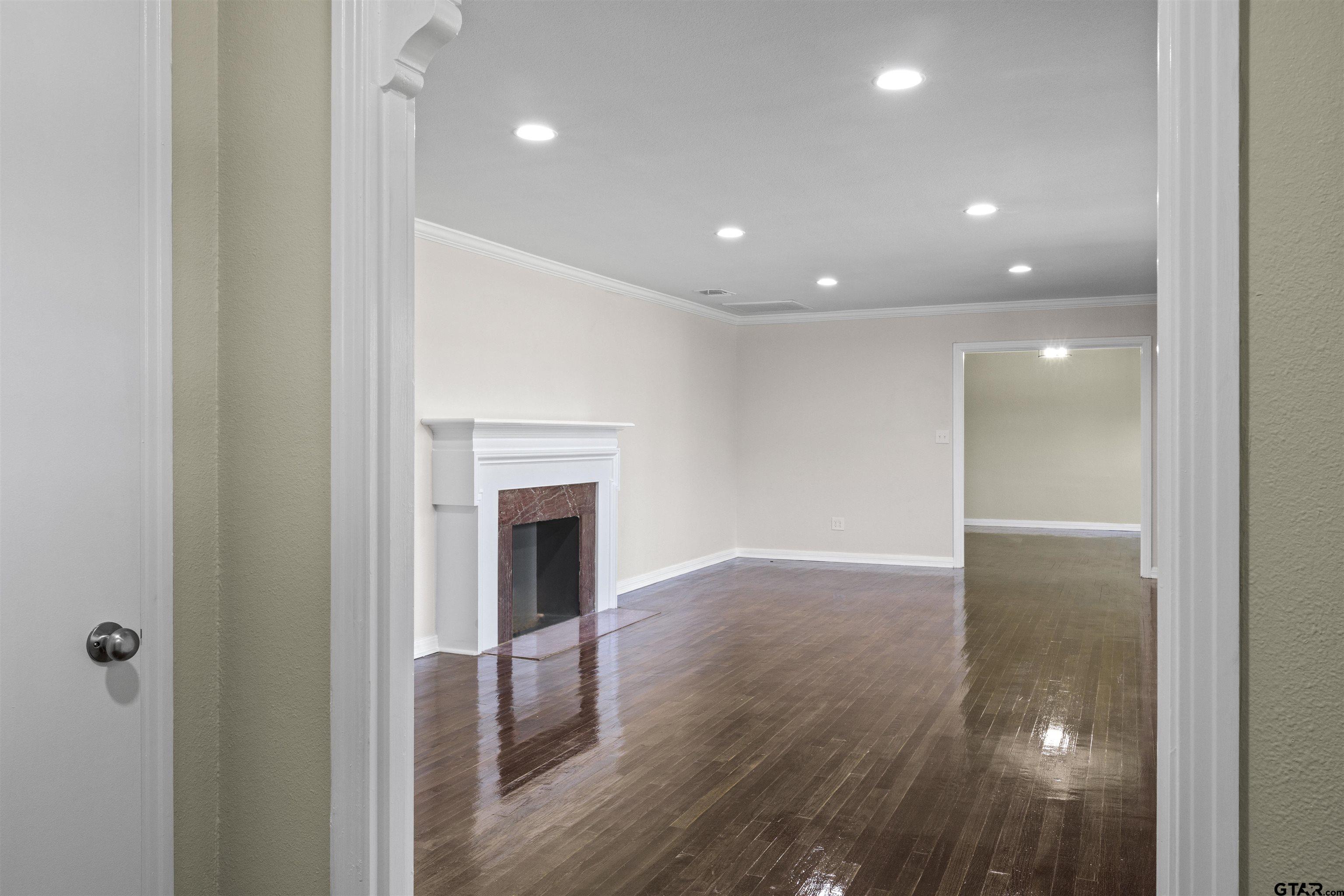 306 Quitman Street Pittsburg, TX 75686 - Photo 7 of 31 a view of a hallway with wooden floor and a fireplace
