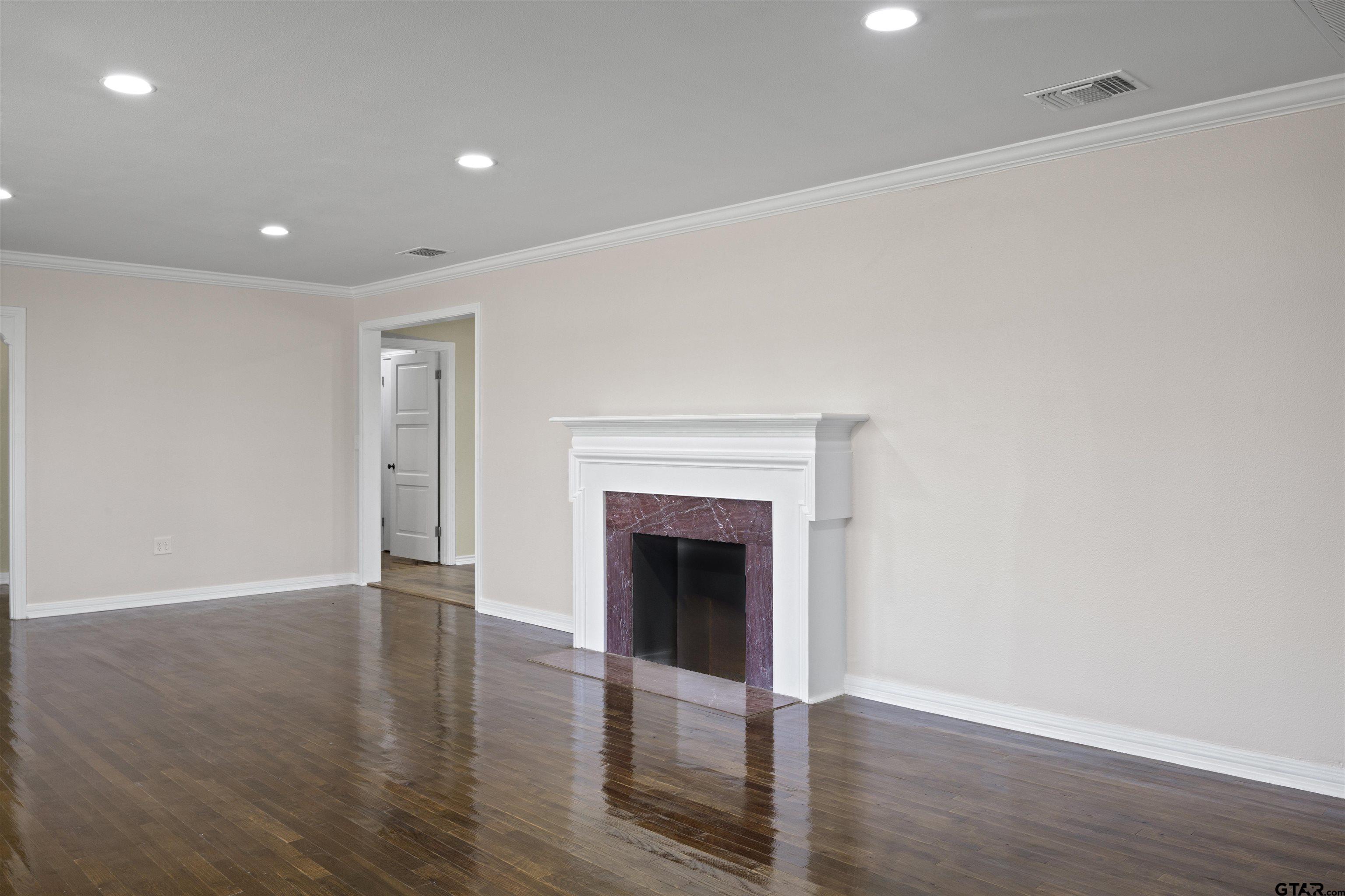 306 Quitman Street Pittsburg, TX 75686 - Photo 8 of 31 a view of an empty room with wooden floor and a fireplace