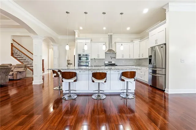 a kitchen with stainless steel appliances granite countertop a sink dishwasher a stove a dining table and chairs with wooden floor