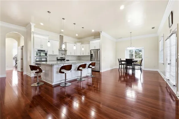 a kitchen with stainless steel appliances granite countertop a sink dishwasher a stove a dining table and chairs with wooden floor