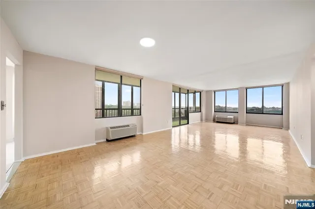 a view of an empty room with window and wooden floor