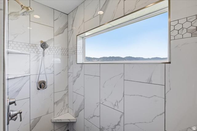 21 Pier Place Tooele, UT 84074 - Photo 37 of 112 Walk-in shower featuring large format tile, a decorative hexagonal tile band, recessed niche, corner shelf, and a horizontal window with mountain scenery