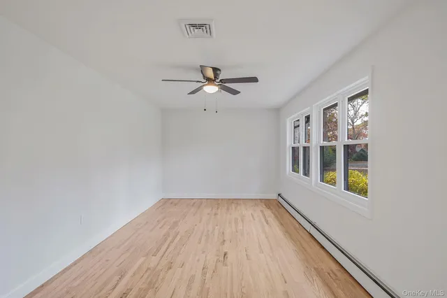 a view of an empty room with a window and wooden floor