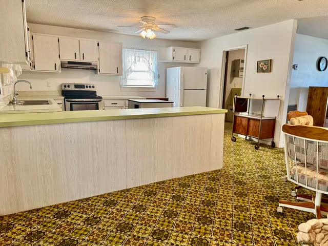 a kitchen with granite countertop a refrigerator and a stove top oven