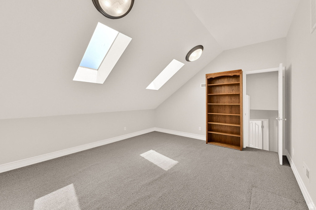 4792 Glasmann Way South Ogden, UT 84403 - Photo 55 of 70 Mutipurpose room carpeted interior space featuring an angled ceiling, two skylights, two flush-mount ceiling lights, and an open doorway revealing interior access via ladder