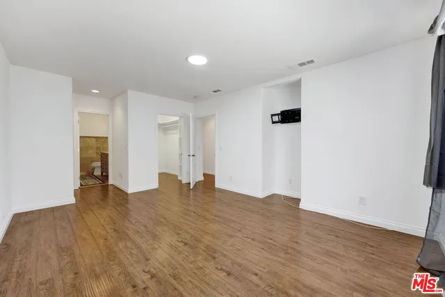 a view of an empty room with wooden floor and closet